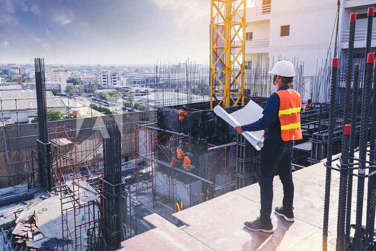 Kiến trúc sư hoặc kỹ sư trên công trường đang xem bản vẽ của tòa nhà